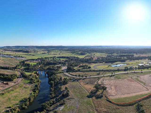 The southern tip of the suburb. Menangle Park ends 114 metres beyond this point, and the Nepean River is the line: the sand and soil quarry in the bend and the motorway's twin spans are Menangle, 2568, in Wollondilly Shire, and the 1863 railway viaduct crosses the river into it. The harness-racing training track sits between the river and the estate.