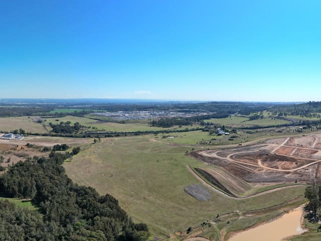 Directly over the junction on Spring Farm Parkway at the northern edge of the suburb — look straight down and it is beneath you. Stage 1 is built; Stage 2 is funded for planning only, and its construction is not funded.