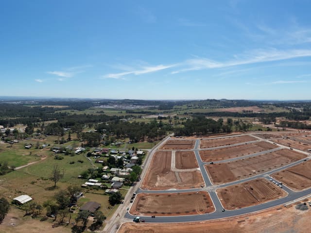 Roads, houses and buildings under construction beside cleared ground.