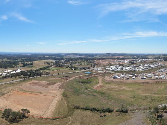 A river bordered by trees, with open land and earthworks beyond.