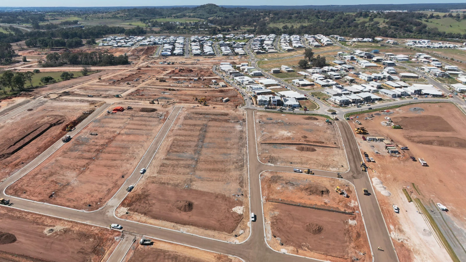 Aerial view of large areas of bare, levelled earth divided by formed roads and kerbs.