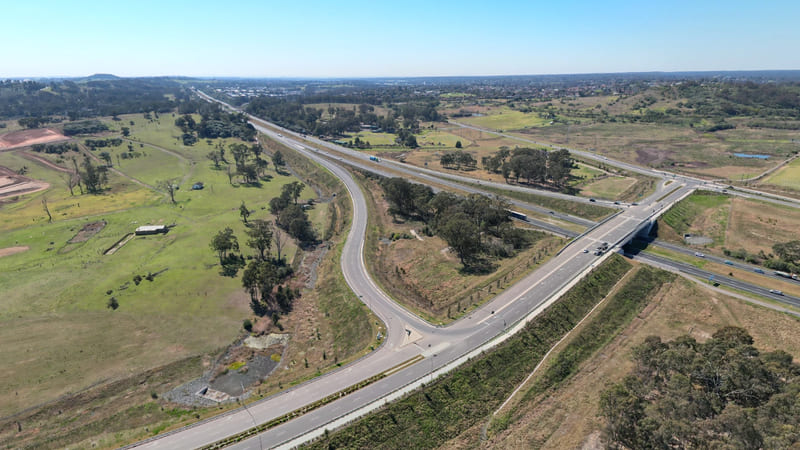 Aerial view of a parkway curving to meet a motorway at an overpass.