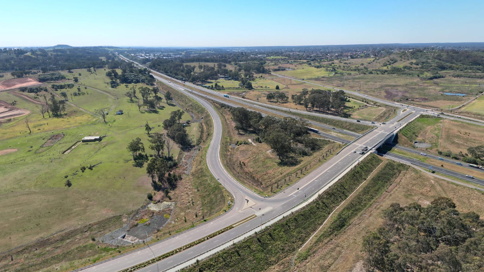 Aerial view of a parkway curving to meet a motorway at an overpass.